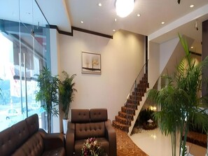 A modern interior with a sofa, a staircase, and potted plants. - S Bee Hotel (Johor Bahru)