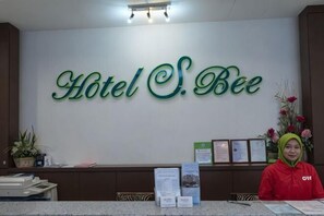 A reception desk with a sign reading 'Hotel S. Bee' and a receptionist. - S Bee Hotel (Johor Bahru)
