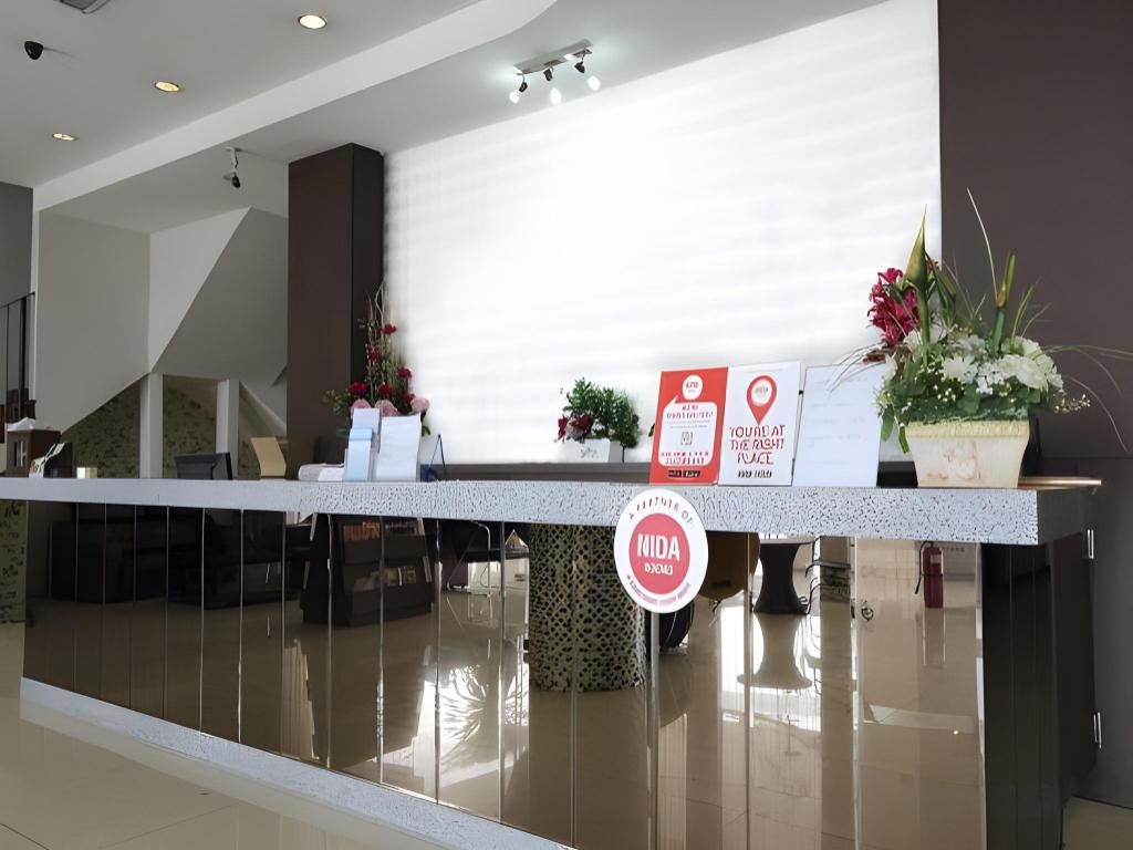 A reception desk with a sign indicating a location, a potted plant, and a wall-mounted sign.