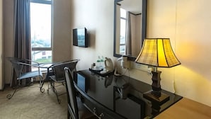 A hotel room with a desk, chair, lamp, TV, and large windows. - S Bee Hotel (Johor Bahru)