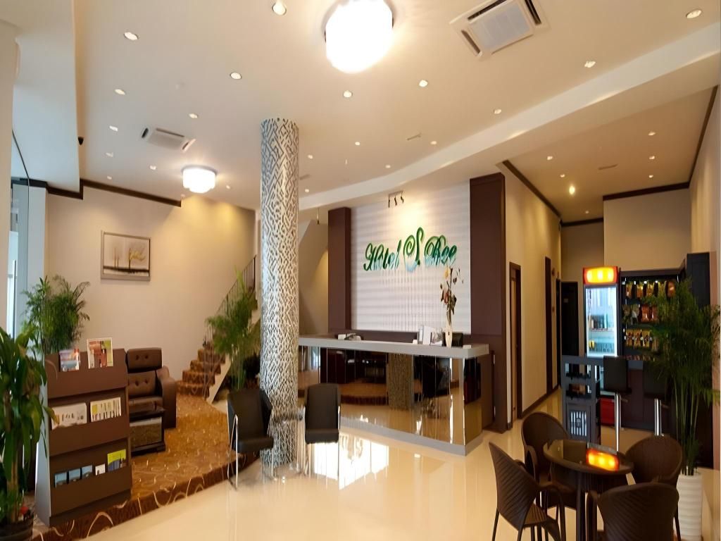 A hotel lobby with a reception desk, seating area, staircase, and a bar.