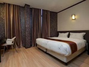 Ein Hotelzimmer mit Bett, Schreibtisch und Vorhängen.