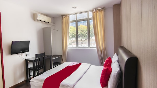 A hotel room with a bed, a desk, a chair, a TV, and a window with curtains. - OYO 89891 1st Inn Hotel Subang (Subang Jaya)