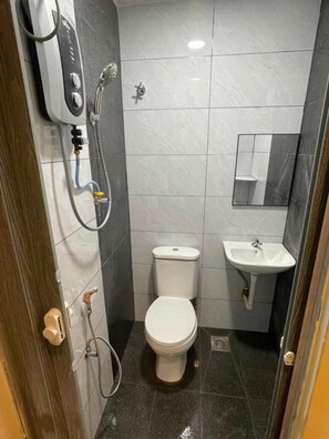A compact bathroom with a toilet, a sink, and a shower unit. - Highway Budget Hotel (Ipoh)