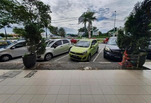 A parking lot with several cars, a gas station, and a large billboard in the background. - Highway Budget Hotel (Ipoh)