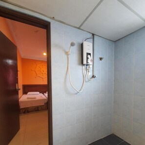 A bathroom with a shower, a toilet, and a sink. There is a bed visible in the adjacent room. - Highway Budget Hotel (Ipoh)