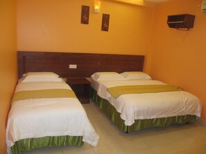 A hotel room with two single beds, a wooden headboard, a nightstand, and a wall-mounted air conditioning unit. - Highway Budget Hotel (Ipoh)