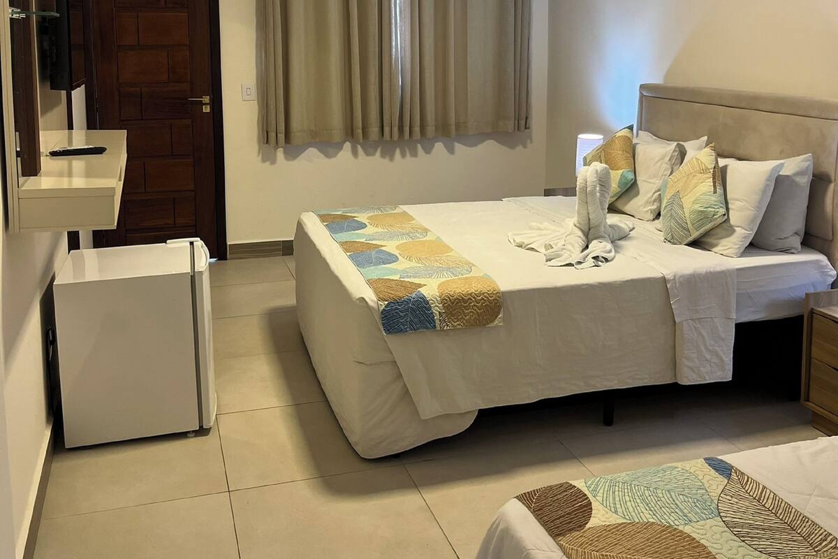 Un dormitorio con cama, mesita de noche y un pequeño armario blanco.