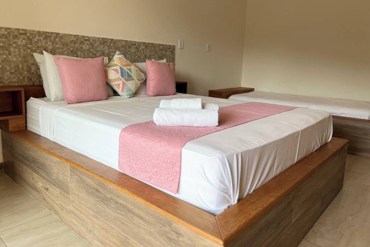 Una habitación de hotel con una cama grande, cabecero de madera y un salpicadero de azulejos.