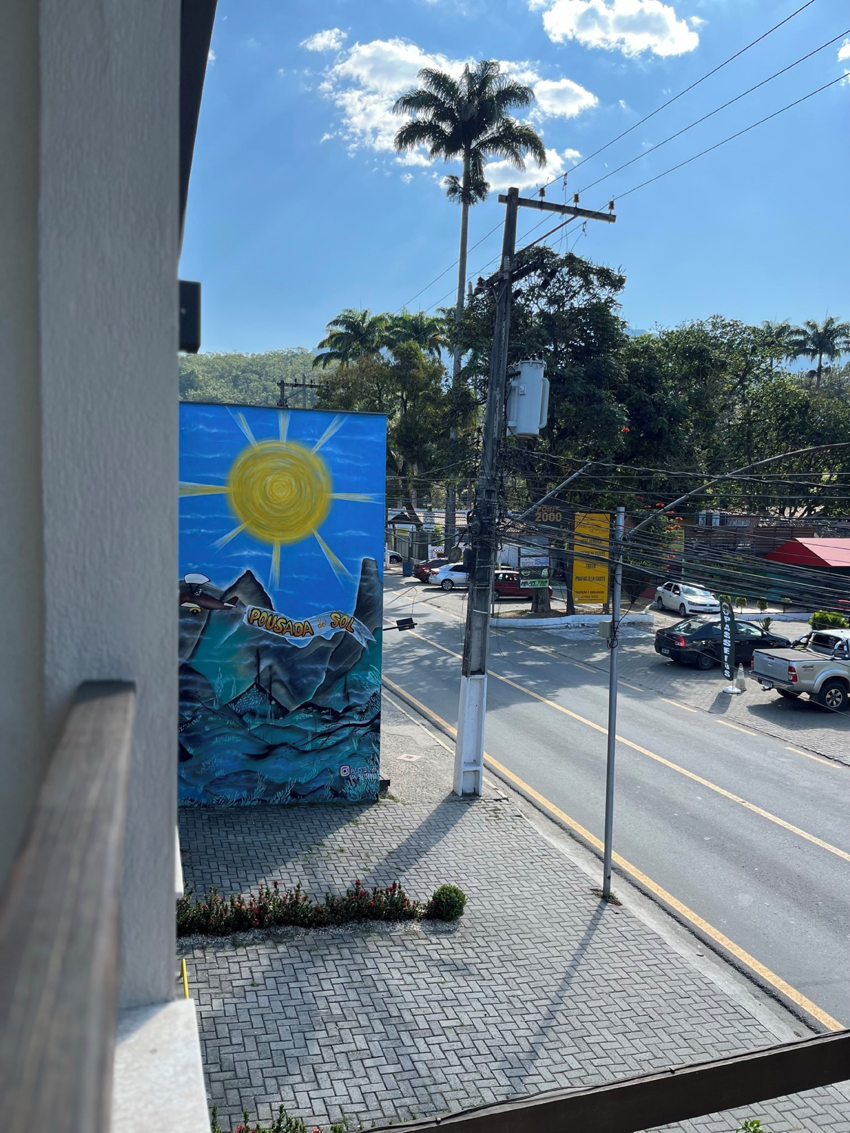 A mural with a sun and mountains on a building's side.