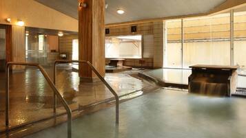 Una piscina interior moderna con una barrera de cristal, columnas de madera y un banco.