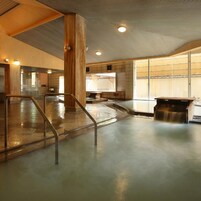 Una piscina interior moderna con una barrera de cristal, columnas de madera y un banco.