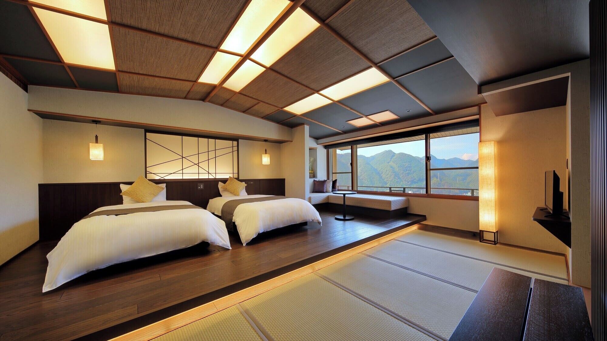 Habitación de hotel con dos camas, vistas a montañas y piso con tatami tradicional.