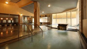 Un amplio espacio interior con piscina que cuenta con varios accesos, una zona de estar central y vistas al exterior a través de grandes ventanales.