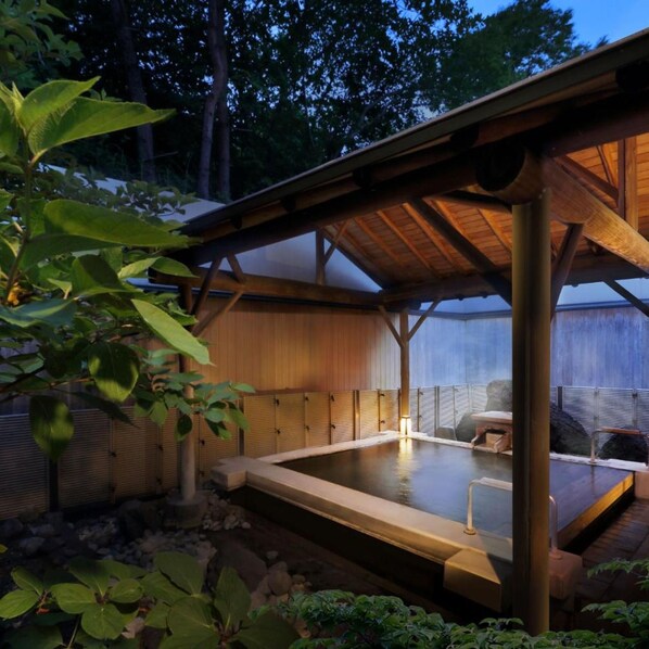 A traditional Japanese onsen with a wooden structure, a hot spring bath, and surrounding greenery. - Genzo No Yu Naruko Kanko Hotel (Osaki)