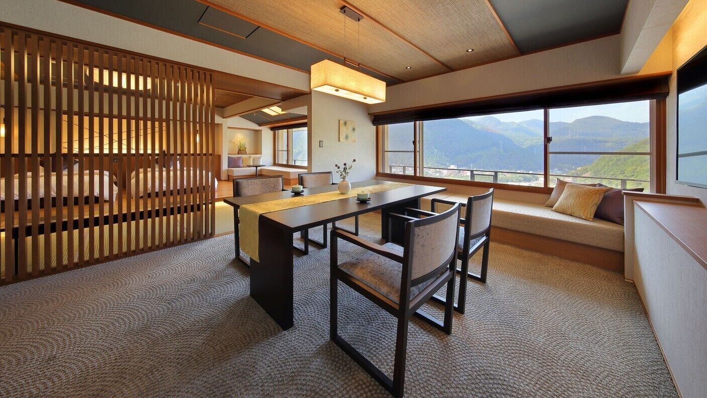 Un interior moderno con zona de comedor, asientos y amplios ventanales con vistas a la montaña.