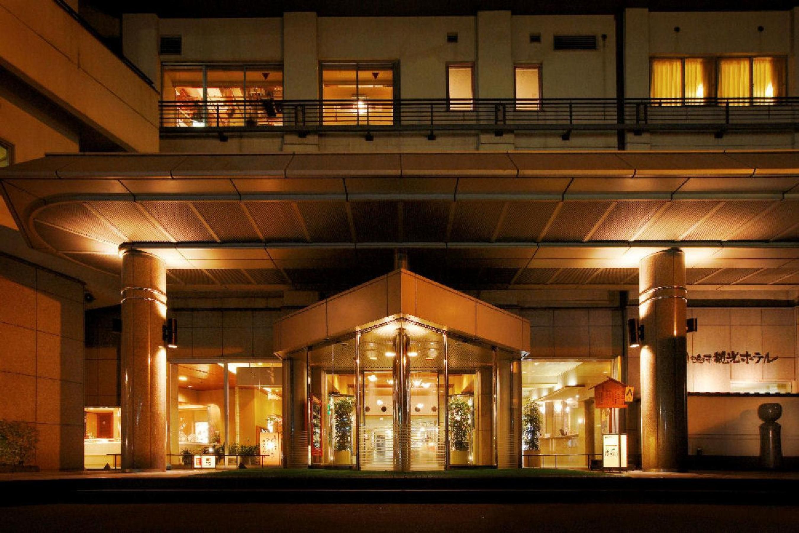 A hotel entrance with a covered lobby, large columns, and a second-floor balcony.