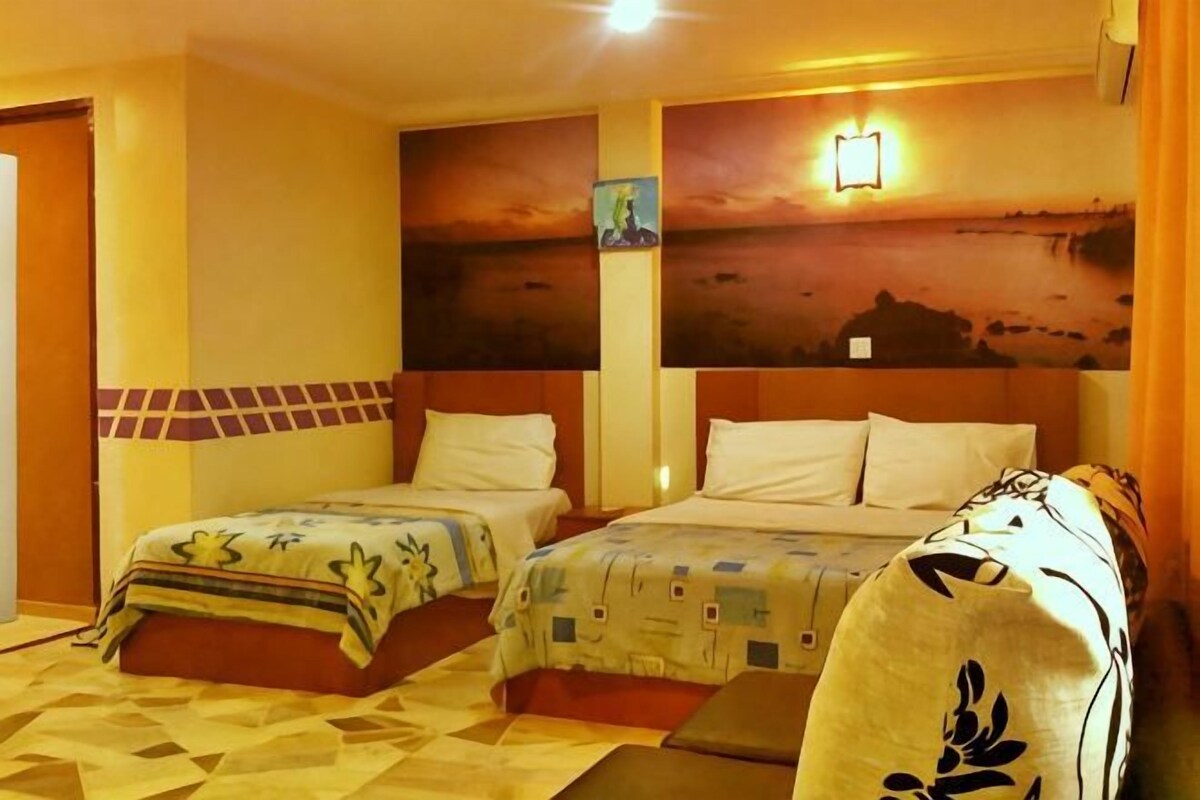 Ein Hotelzimmer mit zwei Betten, einem großen Gemälde an der Wand und einem Nachttisch.