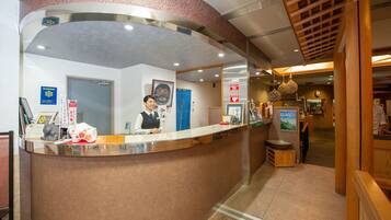 A reception desk with a receptionist, a blue door, and various framed pictures and signs on the wall.