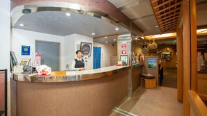 A reception desk with a receptionist, a blue door, and various framed pictures and signs on the wall. - Kaifutei Teradomari Nihonkai (Nagaoka)