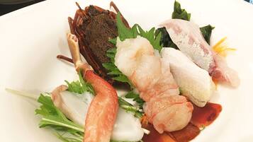 A plate of seafood including shrimp, scallops, and crab legs, garnished with greens.