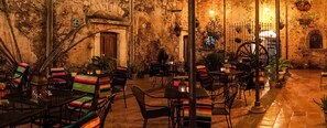 A cozy outdoor seating area with rustic stone walls, wooden doors, and metal furniture. - Hotel Amor y Paz (Real de Catorce)