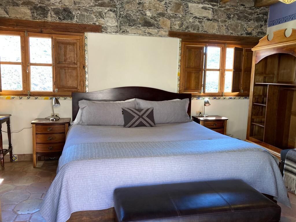 Un dormitorio con una cama grande, cabecera de madera y pared de piedra.