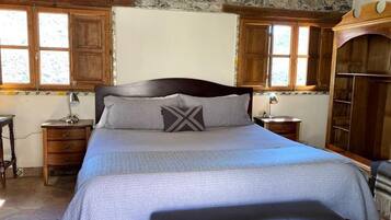 Un dormitorio con una cama grande, cabecera de madera y pared de piedra.