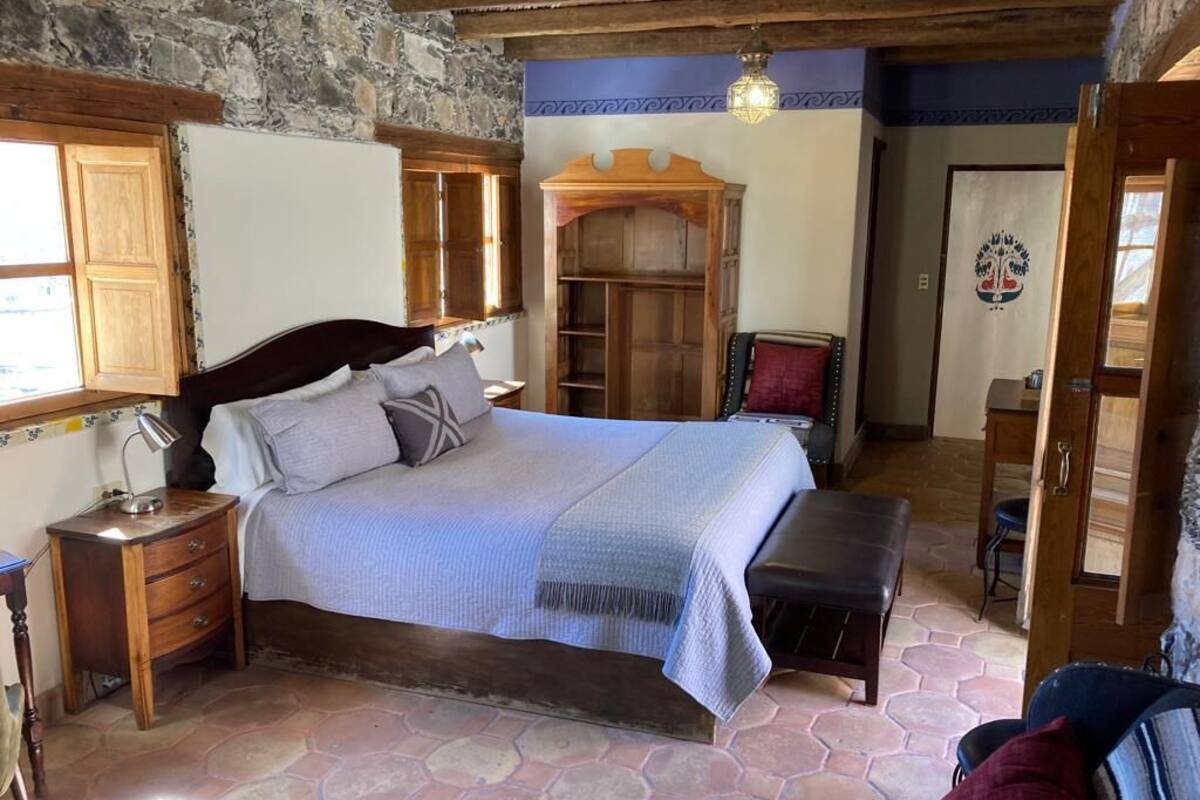 Een slaapkamer met een groot bed, een houten kledingkast en een stenen muur.