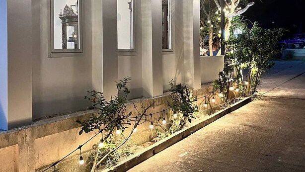 A modern building with a series of illuminated windows and a pathway lined with string lights. - 99 Inn Hotel (Pak Chong)