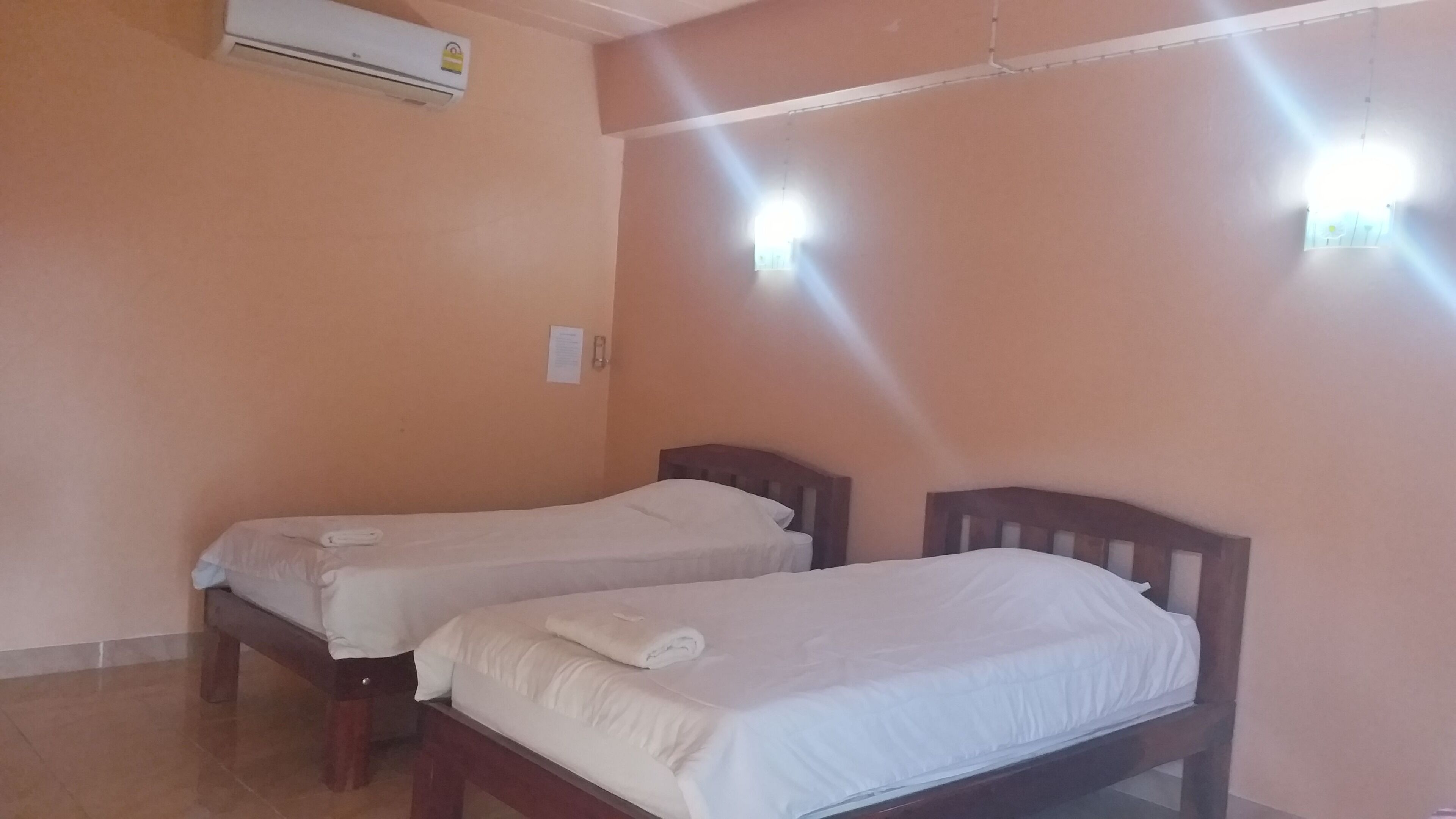 A room with two single beds, a ceiling fan, and an air conditioning unit.