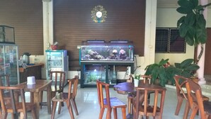 A restaurant interior with wooden chairs, a fish tank, and a refrigerator. - 99 Inn Hotel (Pak Chong)