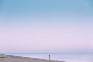 A beach scene with a person walking along the shore.