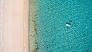 Vue aérienne d’une plage aux eaux turquoise et limpides et au rivage sablonneux.