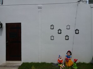 A white wall with a wooden door and five small, square, decorative frames. - Once Upon a Time at Khao Yai (Pak Chong)