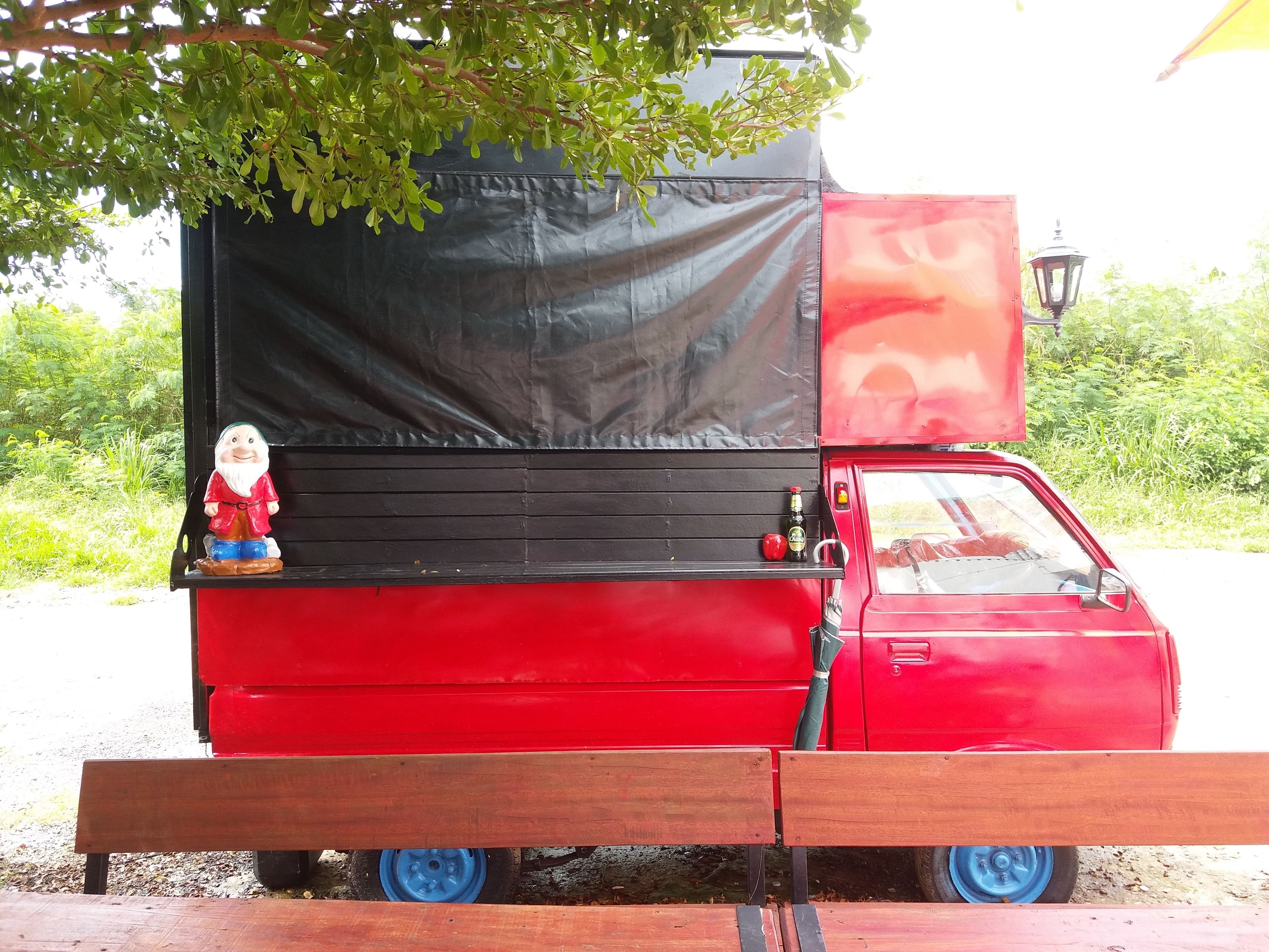 A red truck with a black tarp and a small figurine on the back.