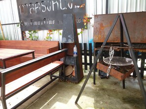 An outdoor seating area with wooden benches and a metal grill station. - Once Upon a Time at Khao Yai (Pak Chong)