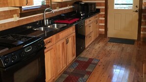 Cocina de cabaña de madera con estufa, pileta y alacenas.