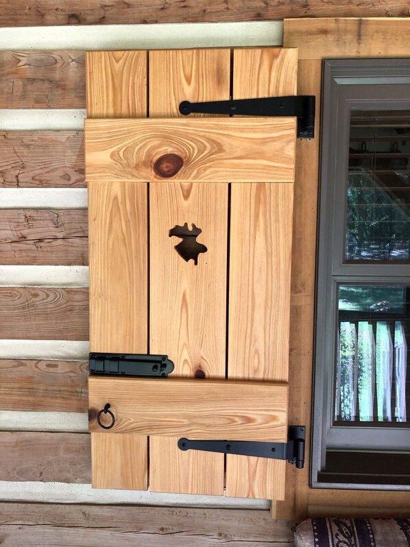 Une porte en bois avec une découpe centrale et des charnières en métal noir.