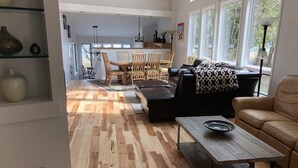 Amplia sala de estar con piso de madera, una mesa de comedor con sillas, un sofá y una mesa de centro.