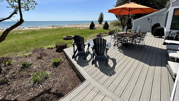 Terraza con mobiliario exterior, una parrilla y vista a la playa.