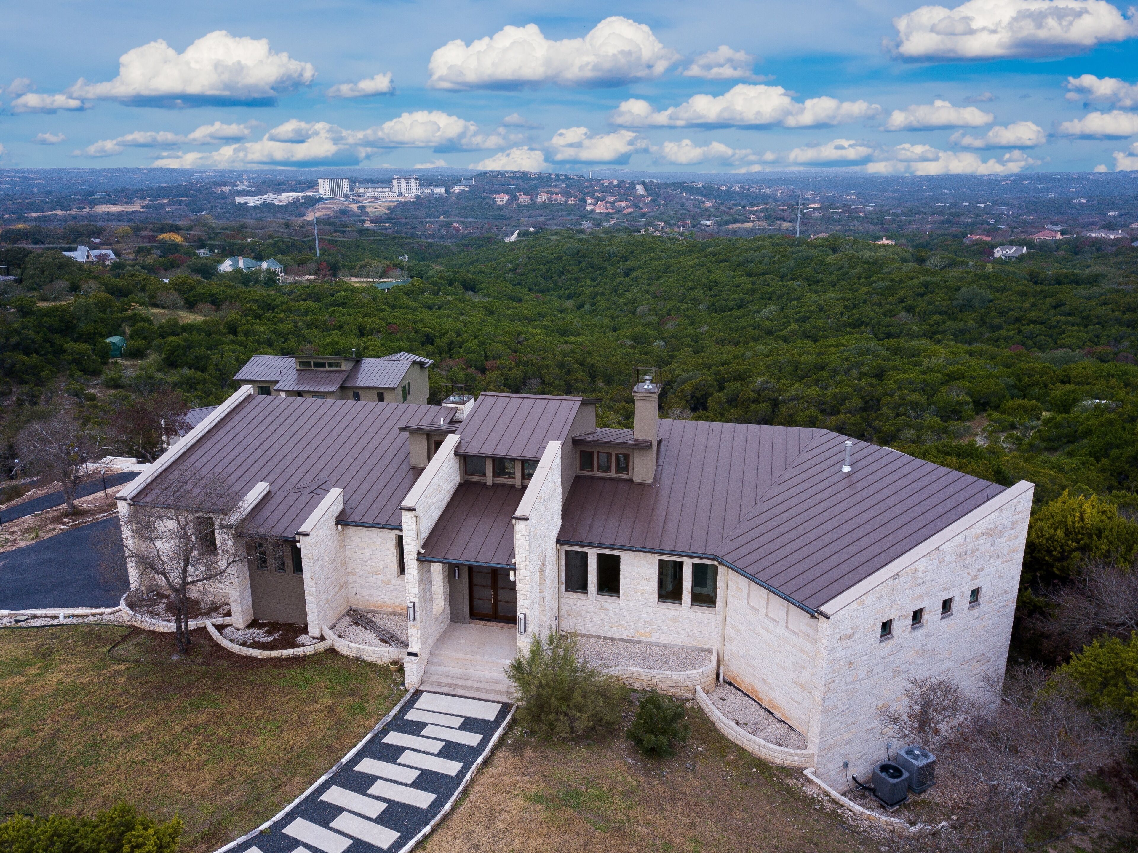 A large, modern house with multiple levels and a spacious front yard.
