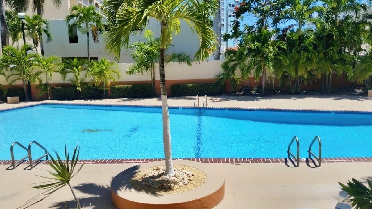 Ein Schwimmbad mit Palmen und einem Gebäude im Hintergrund.