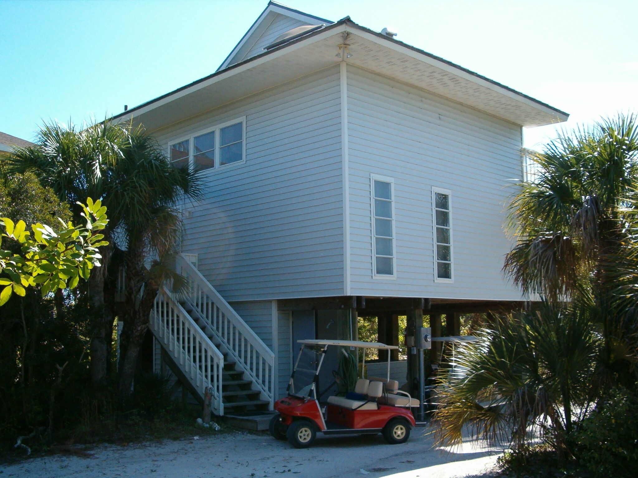 A two-story house with a covered porch and a red golf cart parked outside.