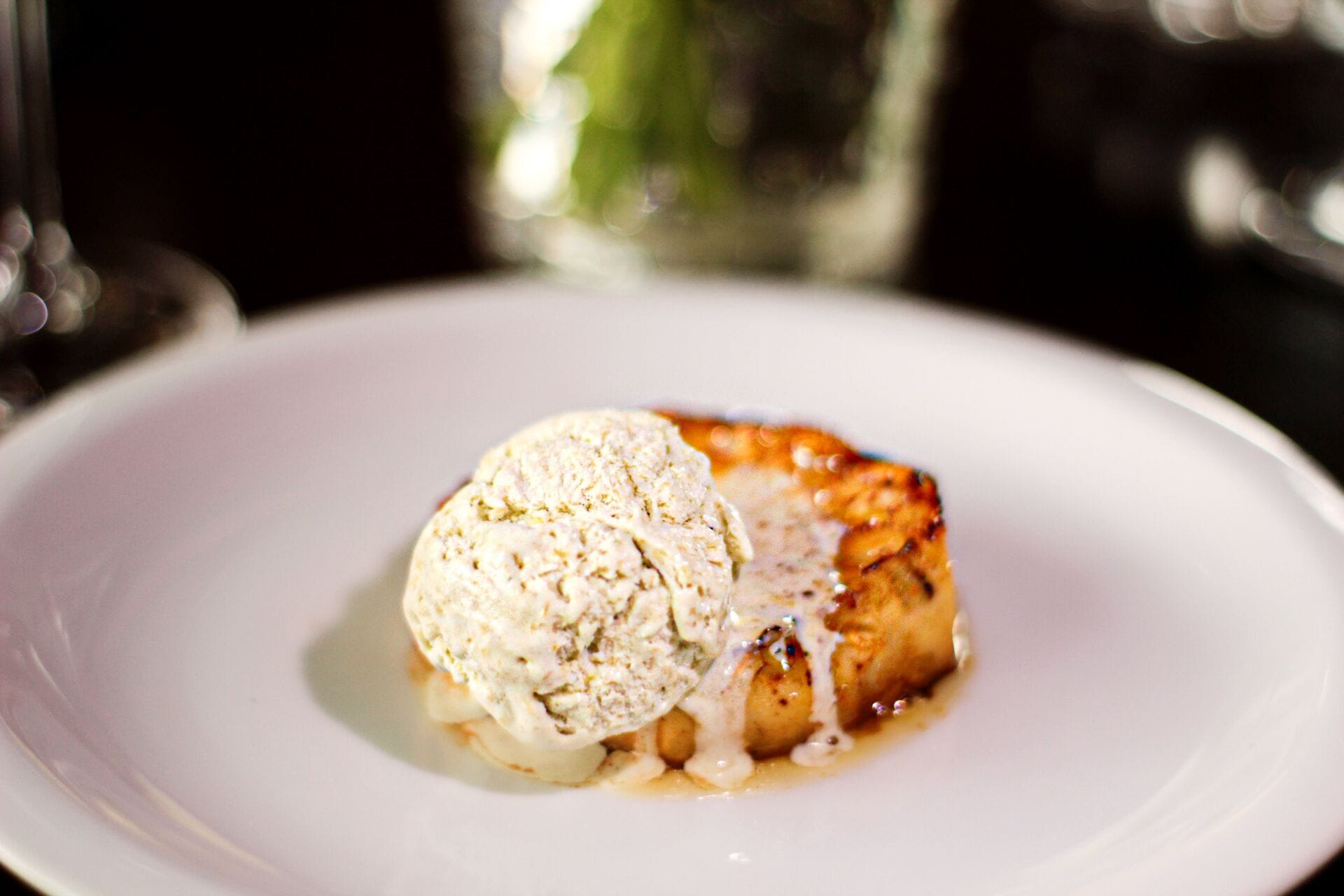 Un postre sobre un plato blanco con una bola de helado encima.