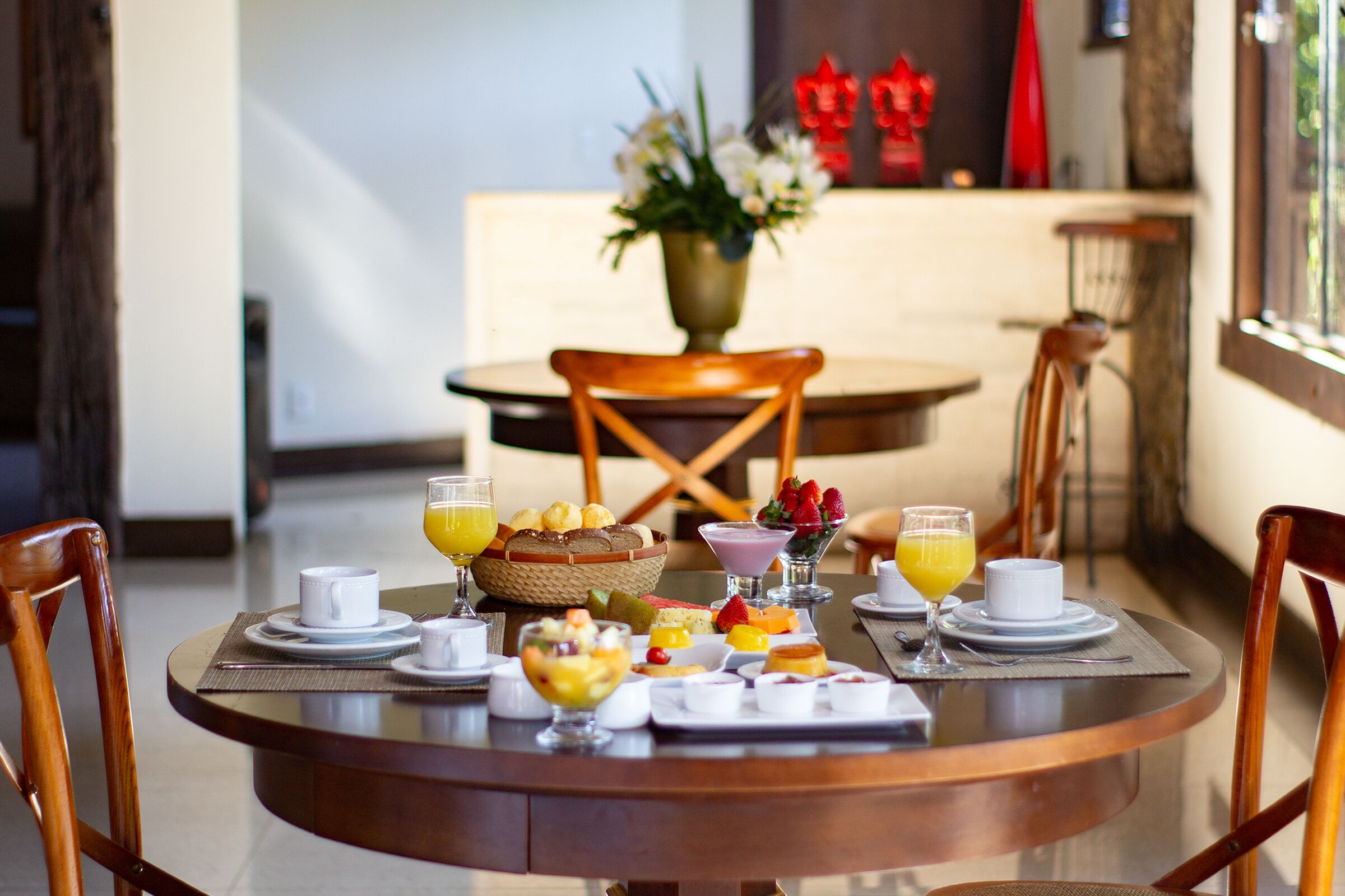 A round dining table with a breakfast setting including fruits, pastries, and beverages.