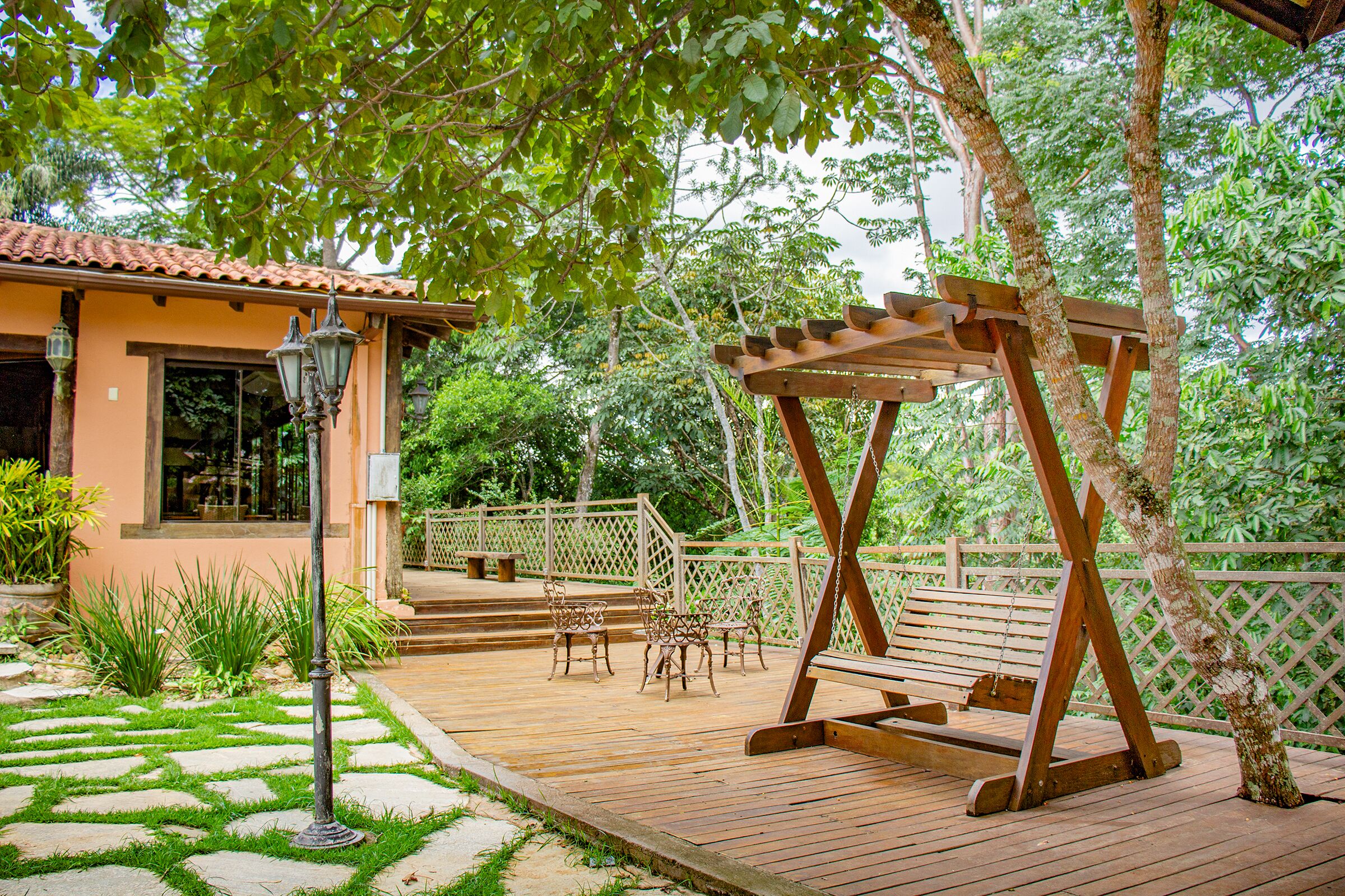 A wooden deck with a swing set, outdoor furniture, and a house with a tiled roof.