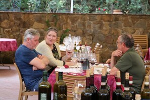 A stone wall with a table set for a meal, surrounded by seated guests.