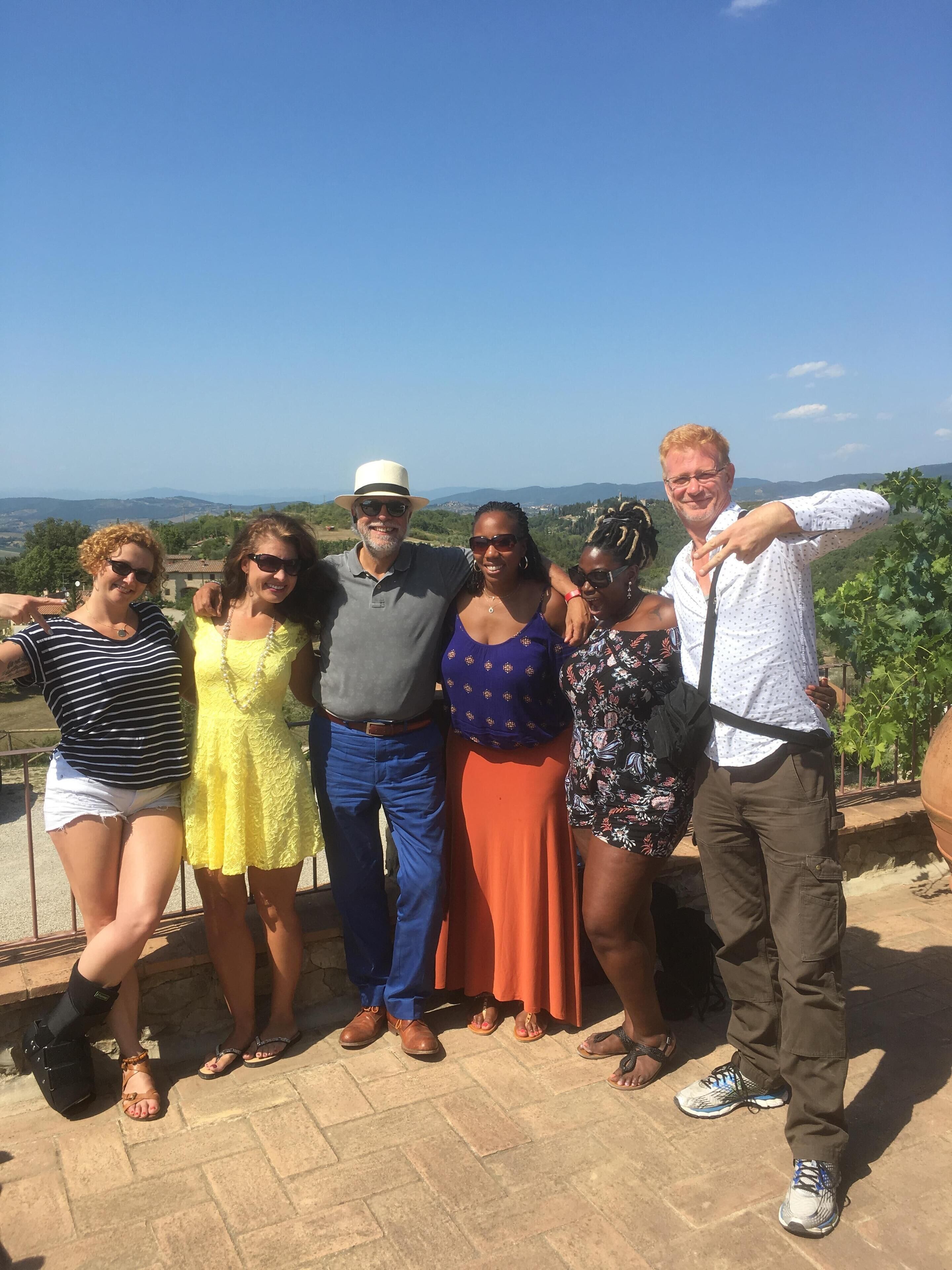 Eine Gruppe von Personen steht auf einer Terrasse mit Panoramablick auf Hügel und Weinberge.