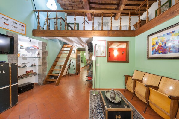 A spacious living area with a wooden staircase, a sofa, a coffee table, and a television.